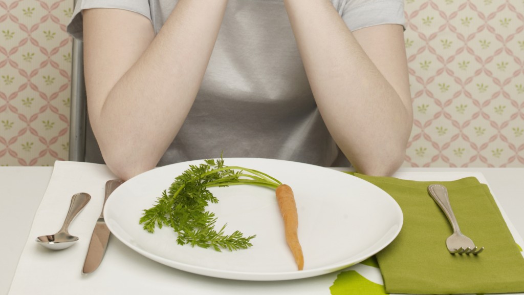 Woman looking at plate with single carrot